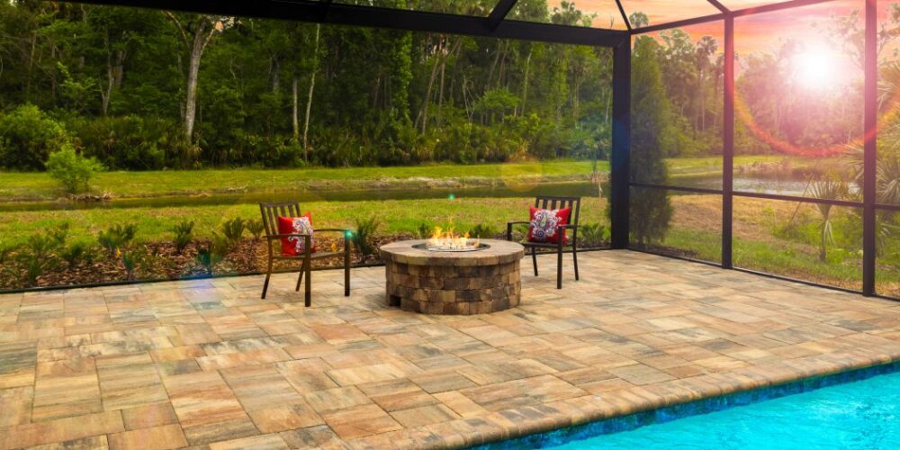 Japandi House pool with stone finish circular fire pit with chairs and sunset through screen enclosure in distance