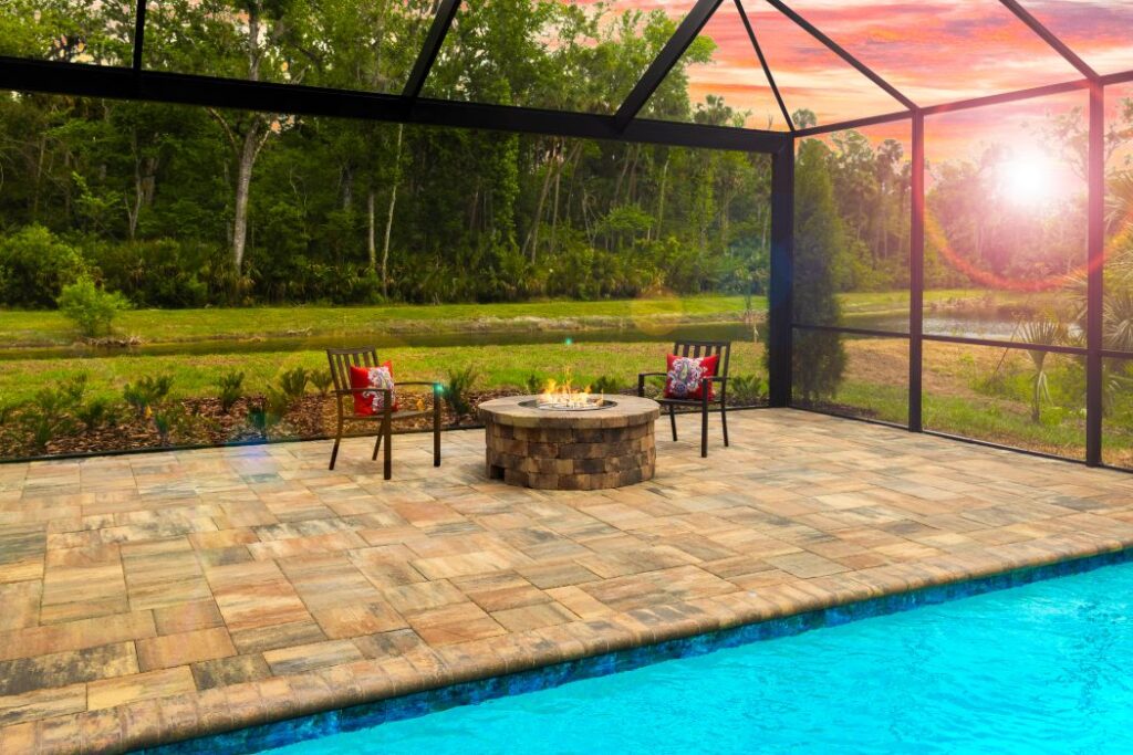 Japandi House pool with stone finish circular fire pit with chairs and sunset through screen enclosure in distance