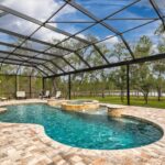 built in pool with curved border and integrated hot tub enclosed within screen canopy