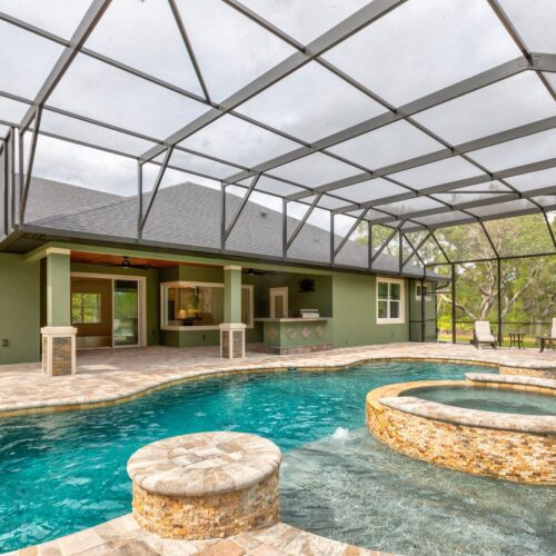 pool with integrated spa inside screen enlosure attached to a residential home