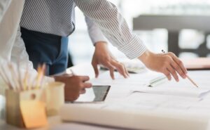 businessman pointing pencil toward location on blueprint document